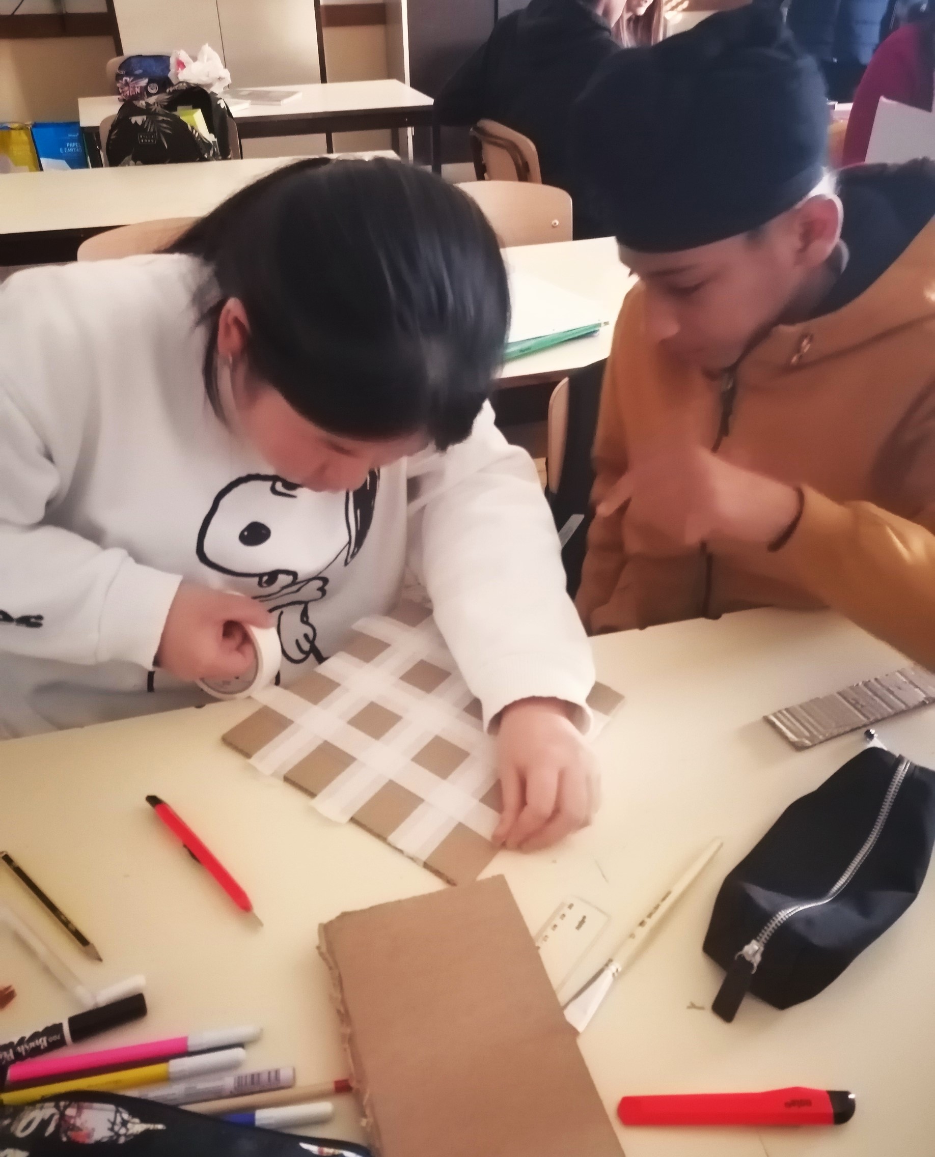 Início da construção do jogo de tabuleiro; os resíduos utilizados foram o cartão para o tabuleiro e tampas de garrafas de plástico como damas.